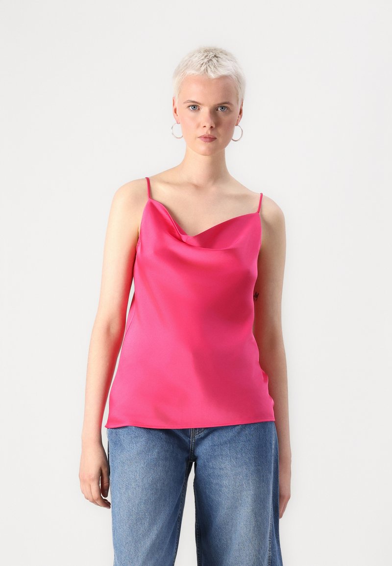 Fuchsia satinkjole med båtutringning, tynne stropper og glatt tekstur. Kombinert med avslappede blå denimjeans.