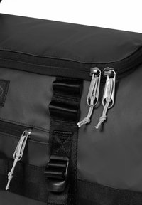 Czarna, wodoodporna torba sportowa z zamkiem błyskawicznym, szarymi uchwytami zamka i regulowanymi paskami. Teksturowana tkanina z trwałymi akcentami metalowymi.