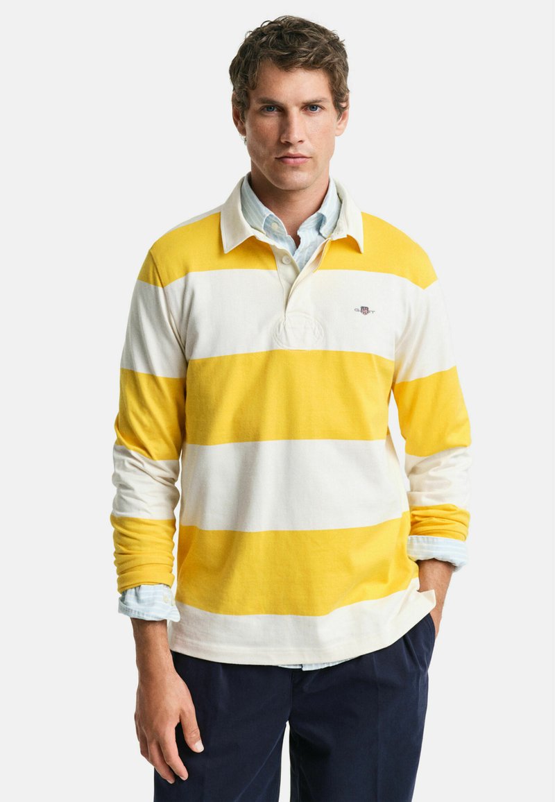Langsleeve rugby shirt in gele en witte horizontale strepen, met een kraag en een klein logo op de linkerkant van de borst.