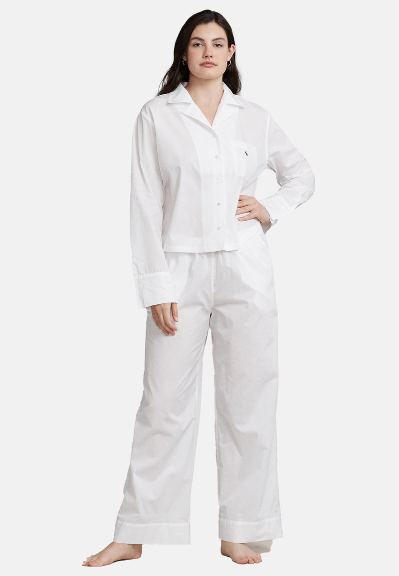 Set di pigiama in cotone bianco composto da una camicia con colletto e bottoni con taschino sul petto e pantaloni larghi con orli risvoltati.