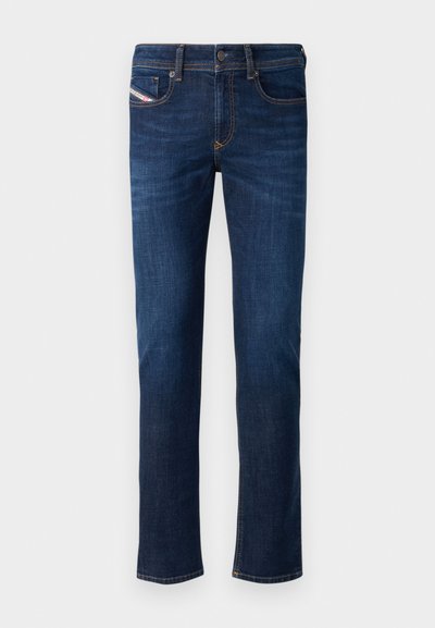 Jean en denim bleu foncé avec une coupe droite, présentant des coutures orange et une petite étiquette de marque sur la poche arrière.