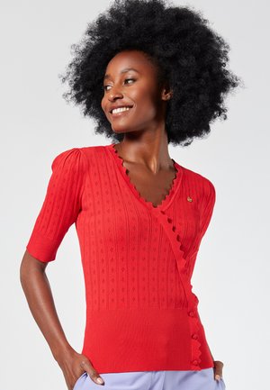 Maglione rosso lavorato a maglia con maniche corte a sbuffo, scollatura scallop e dettagli con bottoni ai lati. Motivo testurizzato su tutta la stoffa.