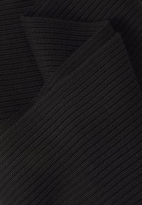 Donkergrijze geribbelde brei stof diagonaal gevouwen, met zichtbare getextureerde verticale lijnen en zachte materiaalfolds.