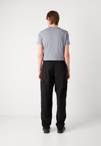 Graues T-Shirt mit kurzen Ärmeln und Rundhalsausschnitt, kombiniert mit schwarzen Cargo-Hosen mit Seitentaschen. Einfaches, lässiges Design.