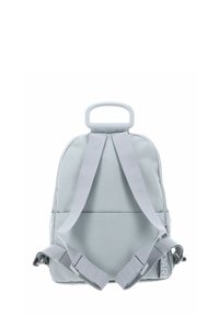 Sac à dos gris clair à forme arrondie, avec bretelles rembourrées et une poignée supérieure. Présente une texture lisse et deux sangles latérales réglables.