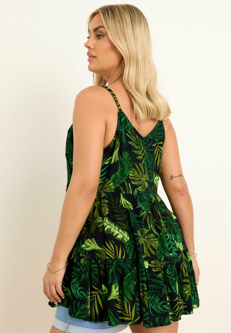 Svart klänning med gröna bladmönster, tunna axelremmar, utfälld nederdel och V-formad rygg. Slät textur, lätt tyg.
