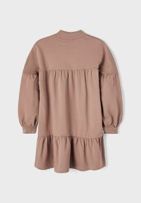 Lys brun kjole med lange ærmer, rund halsudskæring og lagdelt flæse forneden, lavet af blødt stof med en glat tekstur.