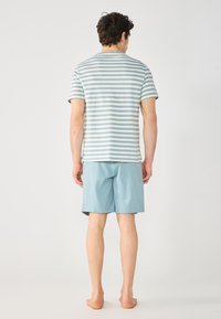 Gestreiftes Hemd mit kurzen Ärmeln in sanftem Blau und Weiß, kombiniert mit hellblauen Shorts. Lässige, bequeme Passform, aus leichtem Stoff gefertigt.