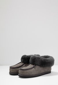 Zapatillas de ante gris con un suave puño de piel de oso gris oscuro, diseño de punta redonda y suela plana de goma negra. Sin marcas o patrones visibles.