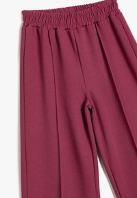 Pantalones burdeos de pliegues con cintura elástica, hechos de un tejido suave. Presentan un ajuste holgado y una textura suave.
