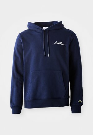 Marineblauwe pullover hoodie met voorvak, verstelbare trekkoordkap, witte cursieve branding op de borst en klein krokodillenlogo op de manchetten.