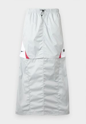 Helehall, pikk spordiseelik, mis on valmistatud läikivast ja siledast materjalist; sellel on punased ja valged detailid, elastne vöökoht ning Nike logo küljel.