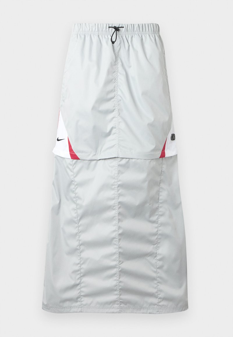 Lichtgrijze, lange sportrok van glanzend, glad materiaal; met rode en witte accenten, elastische tailleband en Nike-logo aan de zijkant.