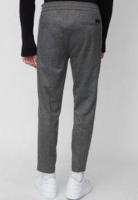 Grå skräddarsydda byxor i ett strukturerat tyg, med en bakficka och resårlinning, i kombination med vita sneakers.