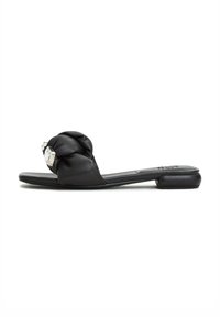 Sandal in pelle nera con parte superiore annodata e un accento decorativo in argento. Suola piatta con tacco minimo, texture liscia.