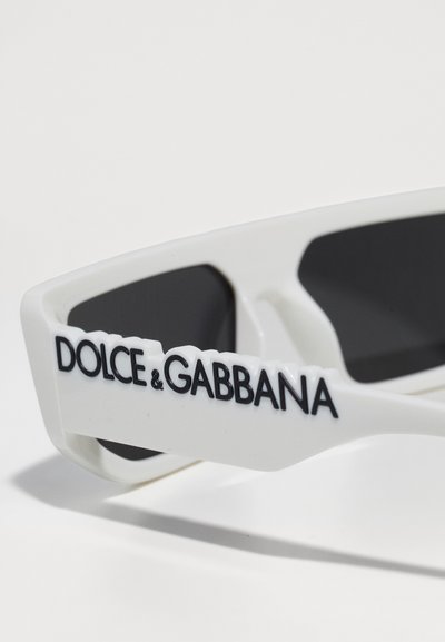 Valged prillid mustade läätsedega; tekstuuriga käepidemed, millel on brändi nimi "DOLCE & GABBANA" rasvaste mustade tähtedega.