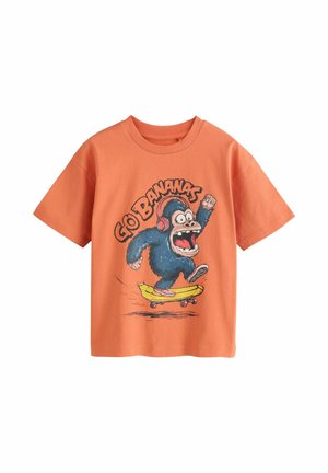 Orange T-shirt med en animeret blå gorilla, der har hovedtelefoner på, og som står på skateboard på en banan, med teksten "Go Bananas" over.