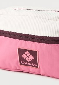 Ροζ και λευκή θήκη με φερμουάρ, με υφή υφάσματος και ραμμένη μπροστινή ετικέτα με το λογότυπο της Columbia.