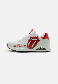 Vita sneakers med röda detaljer, med en tunga som har en logotyp och texten "the Rolling Stones." Slätt material med en strukturerad sula och luftkuddar.