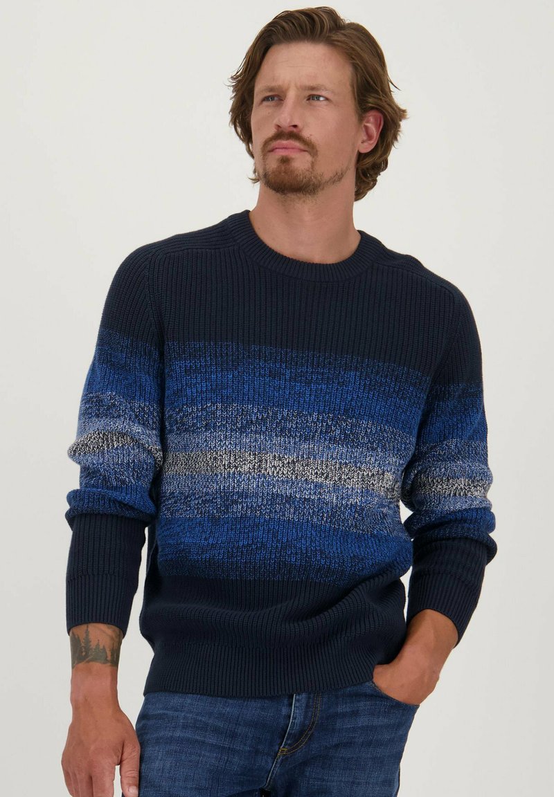 Gebreide trui in een marineblauwe, blauwe en grijze gradient; voorzien van een geribbelde ronde hals en manchetten; textuur stof. gedragen met denim jeans.