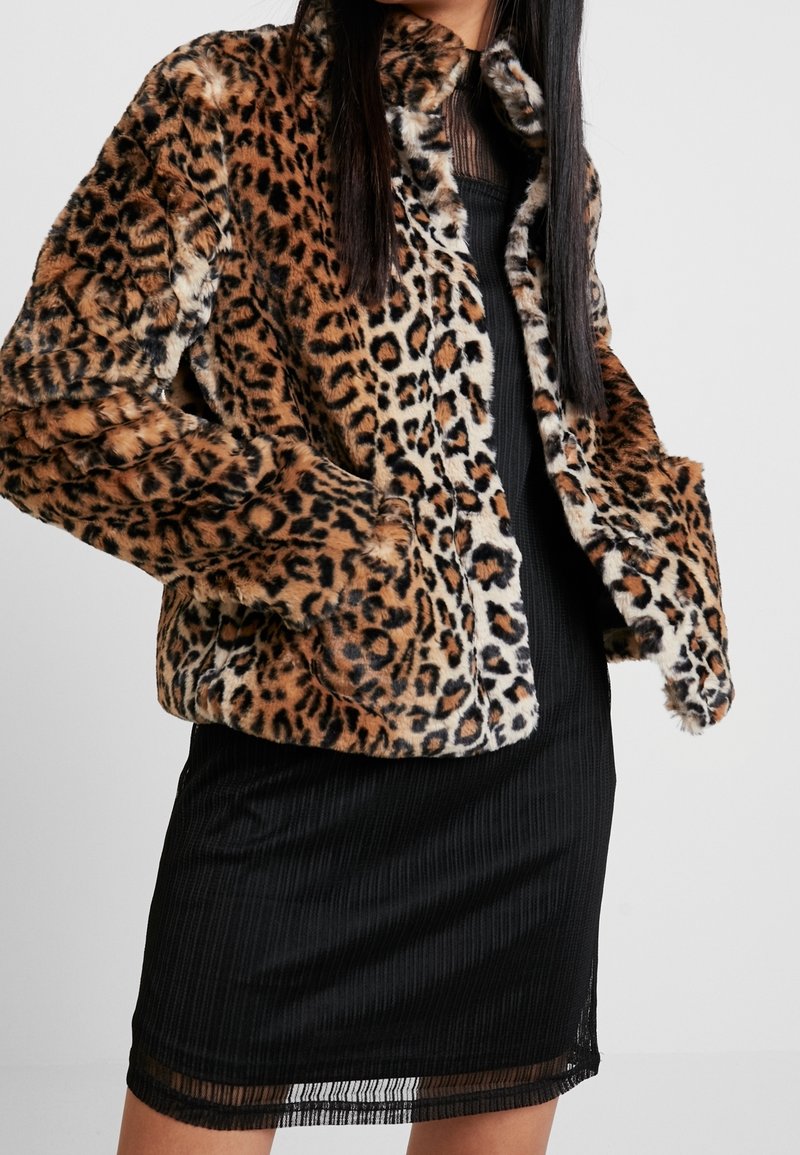 Leopardprint faux fur jakke med en blød tekstur, forlommer og krave. Bæres over en sort ribbet kjole.