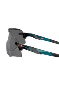 Occhiali da sole sportivi con una elegante montatura nera e accenti teal, dotati di una grande lente grigia scura e bracci laterali texturizzati.