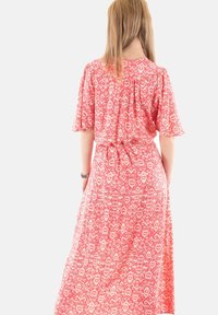 Vestido maxi con un estampado de corazones en rosa y blanco, con mangas cortas, cintura ajustada y falda fluida. Tejido suave con una textura ligera.