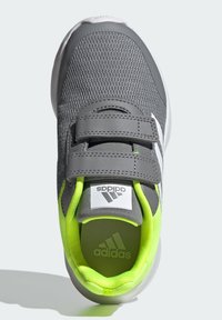 Chaussure de sport grise avec tige en maille, deux bandes Velcro grises et accents vert lime. Présente le logo Adidas et un intérieur rembourré.