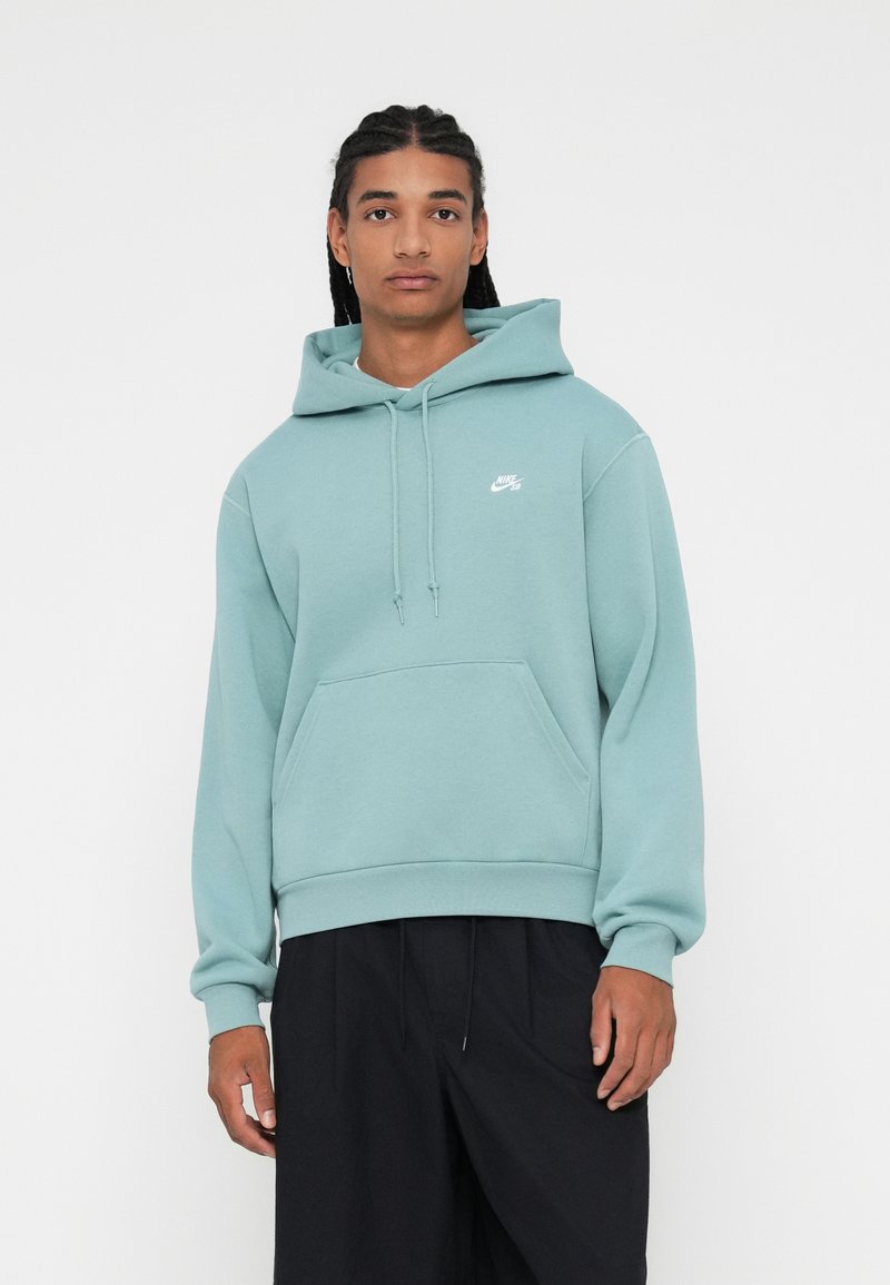 Sudadera verde claro de algodón, con un bolsillo frontal tipo pouch, capucha con cordón y un pequeño logo blanco en el pecho. Diseño de corte holgado.