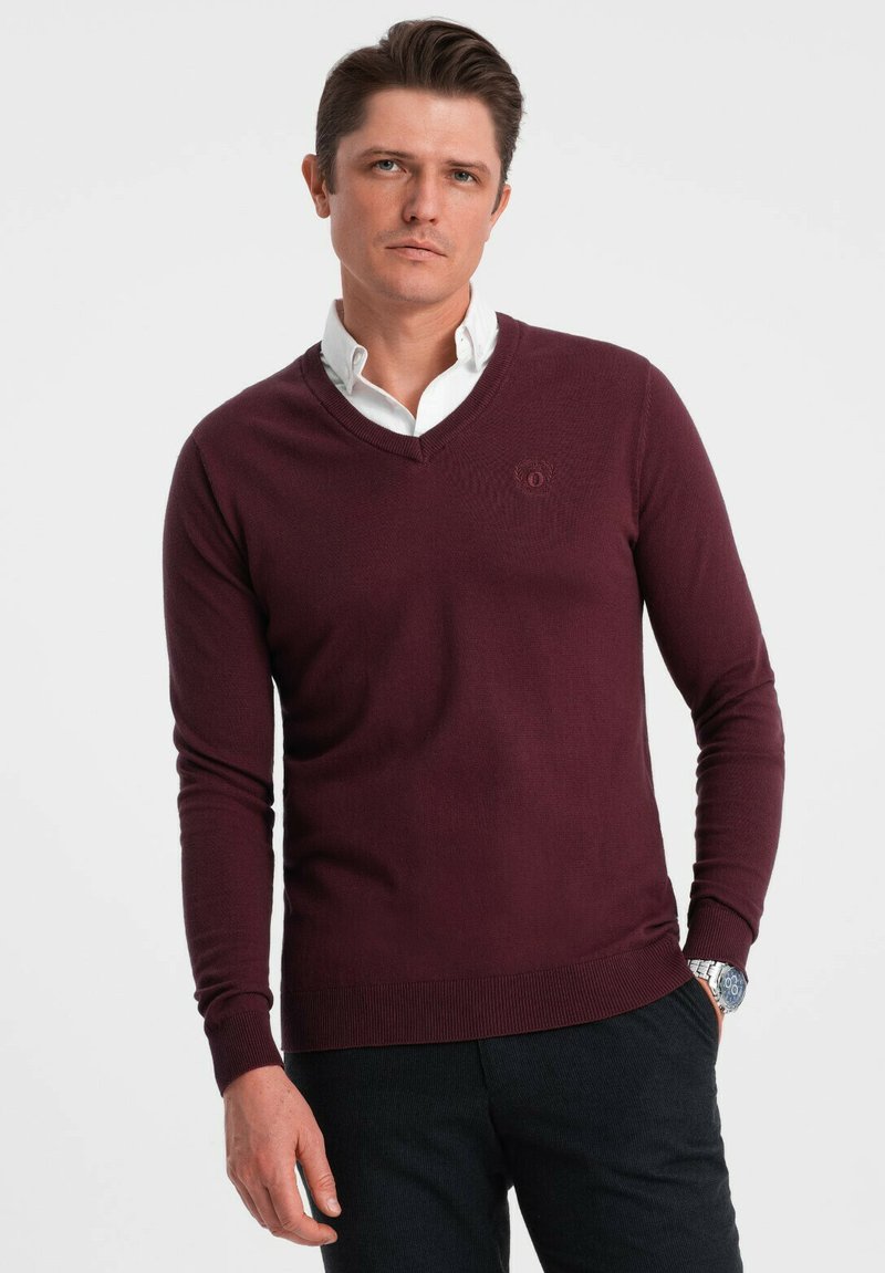 Burgundy v-ringad tröja i stickad kvalitet, med en tajt passform, ribbade mudd och nederkant, samt en diskret logotyp på bröstet.