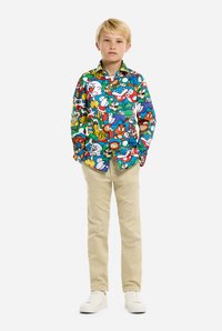 Kleurvol langarm T-shirt met cartoonfiguren op een blauwe achtergrond; met knopenkraag, beige broek en witte schoenen.