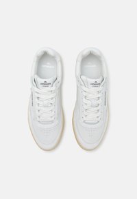 Baskets en cuir blanc avec détails perforés, semelle extérieure claire contrastante et marquage proéminent sur la languette. Fermeture à lacets.