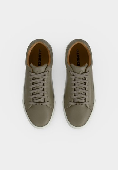 Paire de baskets en cuir vert olive à lacets avec semelles blanches, vues de dessus sur fond blanc.