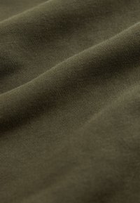 Olivgrönt tyg med en slät, texturerad yta och fin ribbning, som visar mjuka veck och naturliga skrynklor.