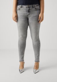 Gray skinny jeans with a frayed hem, featuring a classic five-pocket design and a subtle faded texture, paired with silver high heels.