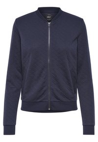 Marinblå quiltad bomberjacka med dragkedja fram, ribbade ärmslut och nederkant. Har två sidofickor och rundad halsringning. Mjuk tygtextur.