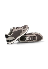 Zapatillas deportivas en gris y beige, que presentan una combinación de materiales lisos y texturizados, puntera redonda, diseño de cordones y una suela de goma gruesa.