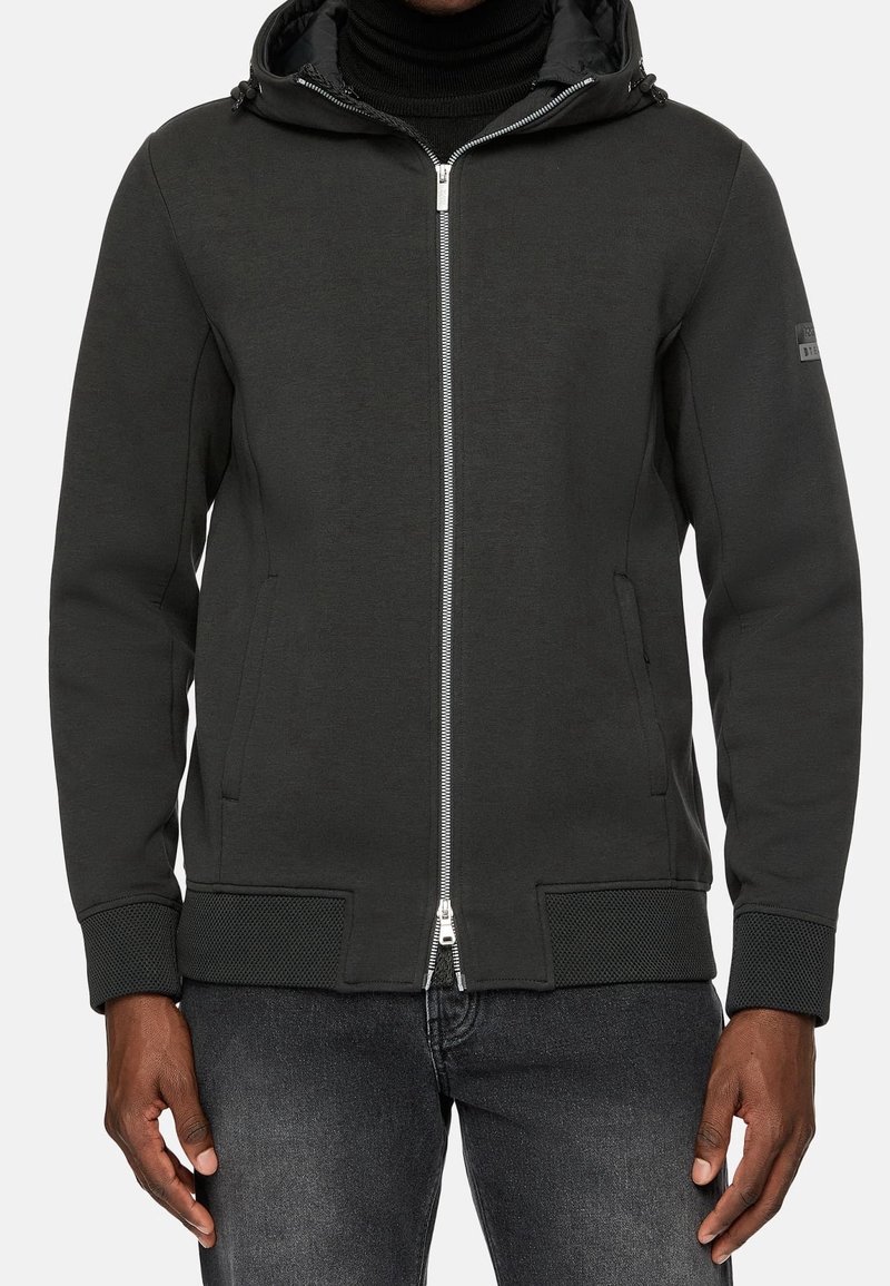 Dark gray zip-up hoodie with a textured mesh trim, featuring a hood and side pockets. Front zipper and subtle branding on the sleeve.