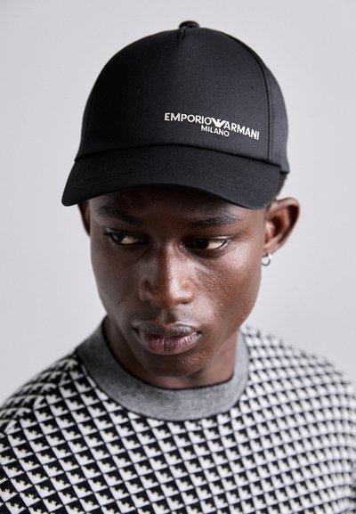 Casquette noire avec logo brodé "Emporio Armani Milano", fabriquée en tissu lisse, avec une visière incurvée et un design ajusté. Pull à motif texturé.