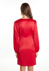 Rochie roșie din satin cu un corset ajustat, mâneci lungi puffate și o margine dreaptă. Textură netedă și detalii minime la spate.