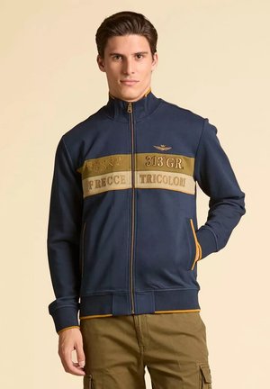 Felpa navy con zip e dettagli dorati, caratterizzata da un design a strisce sul petto con il testo "313 GR," "FRECCE," e "TRICOLORI", e polsini a coste.