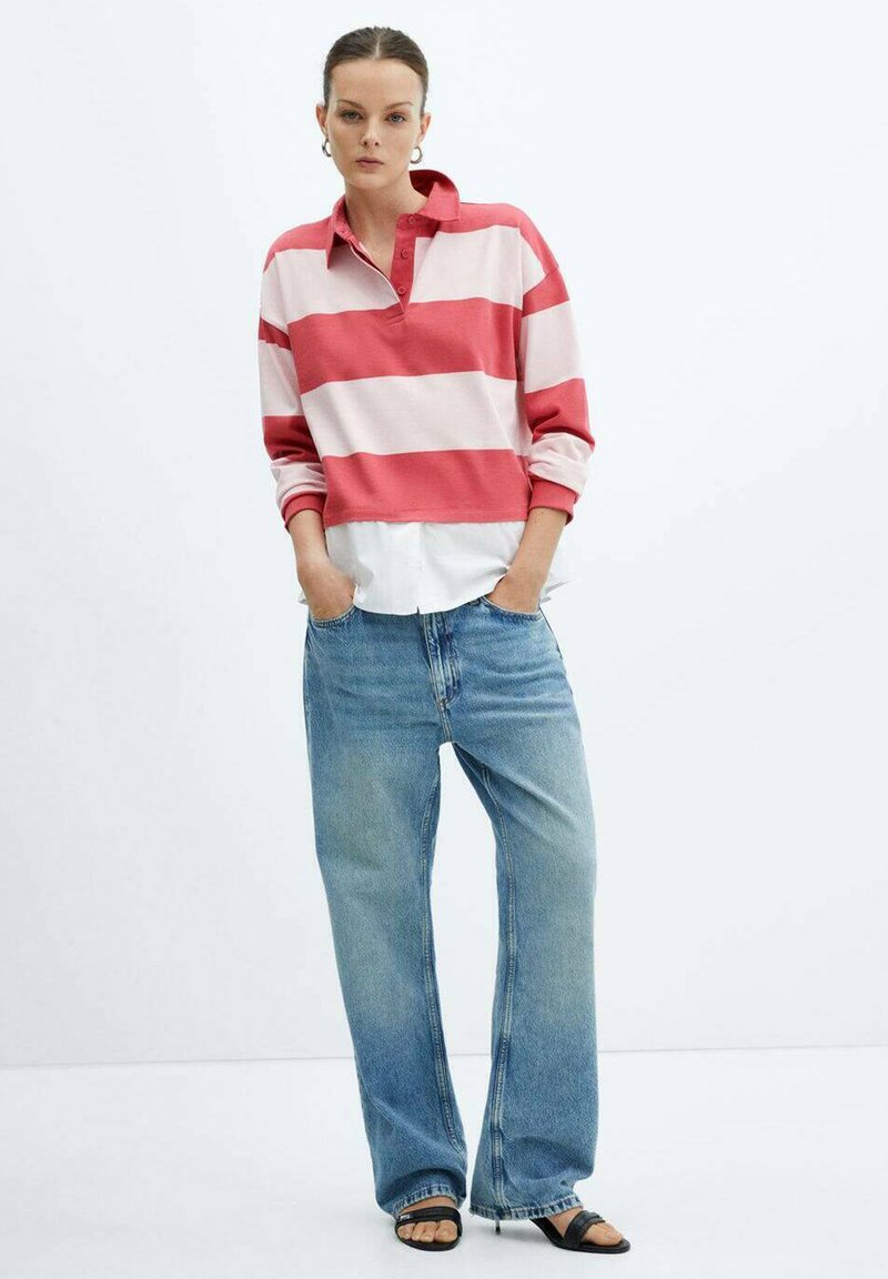 Polo a maniche lunghe a righe rosse e rosa chiaro, abbinato a jeans in denim blu larghi. Il modello indossa sandali neri. Design di un outfit casual.
