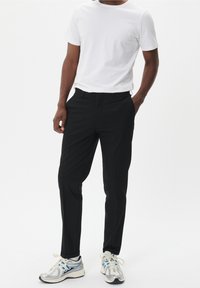 Svarta kostymbyxor med rak passform och slank design. Tillsammans med en enkel vit t-shirt och silverskor med blå detaljer.