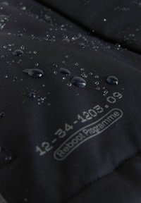 Wasserabweisender schwarzer Stoff mit sichtbaren Wassertropfen. Mit grauem, gedrucktem Text: "12-34-1203.09 Reboot Programm." Glatte Textur.