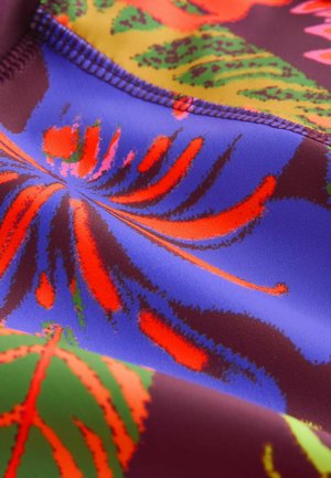 Värikäs, kuvioitu kangas, jossa eloisat punaisen ja oranssin sävyiset kukkakuviot sinisellä ja violetilla taustalla; sileä pinta, joustava materiaali.