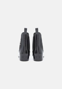 Bocanci negri din piele lacuită, cu panouri elastice pe părțile laterale și tab-uri pentru tragere, având un design elegant și un toc mic, rotund.