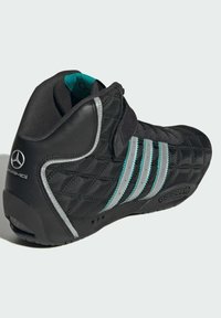 Čierna športová vysoká topánka s prešívanou textúrou, s tromi striebornými pruhmi a akcentmi v teal farbe, a detailom loga na zadnej strane.