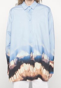 Long-sleeve button-up shirt in light blue with a gradient pattern transitioning to brown and black. Smooth fabric; classic collar with cuffs.