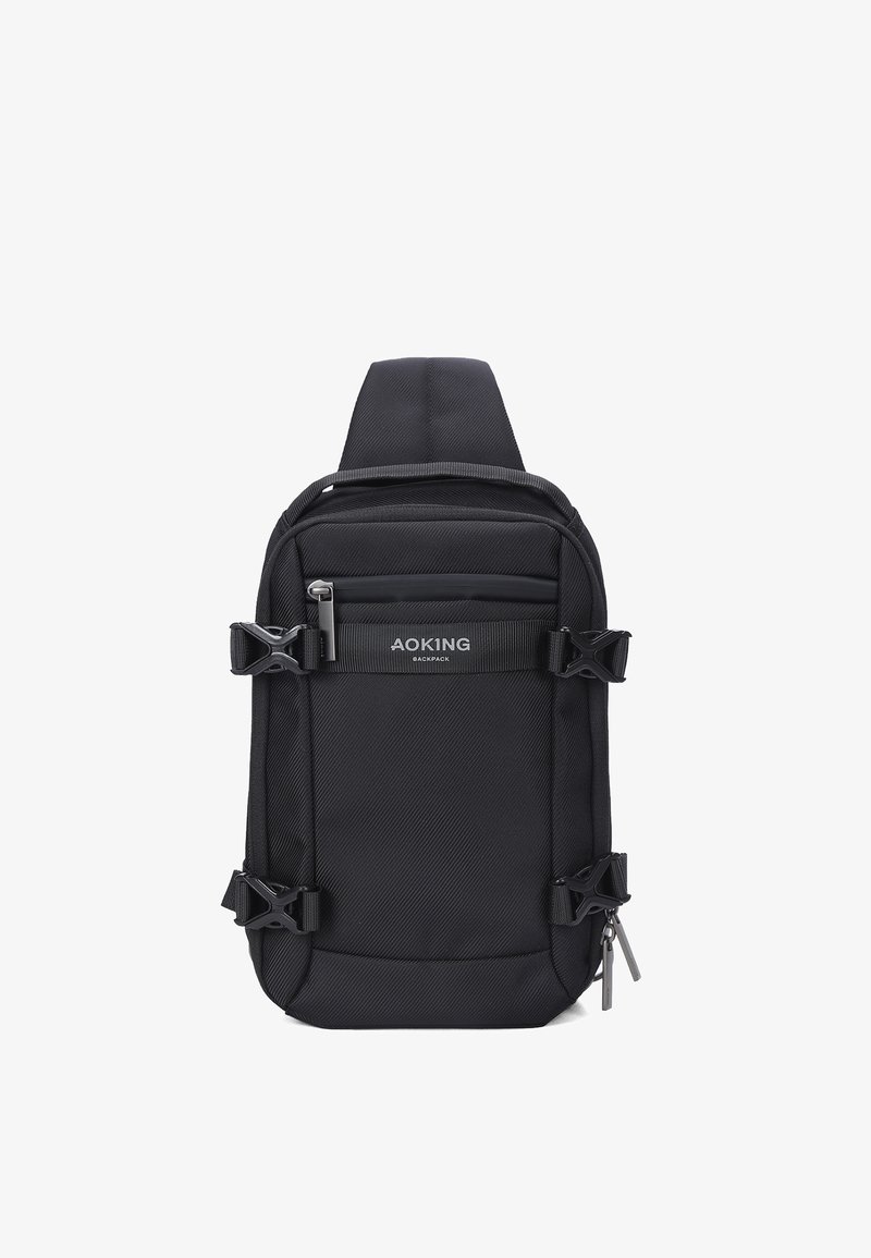 Sac à dos bandoulière compact noir avec clips latéraux ajustables, poche avant zippée et une large sangle d'épaule.