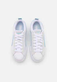 White sneakers with light blue accents, smooth leather and textile materials, flat laces, and a textured sole. Logo displayed on the sides.